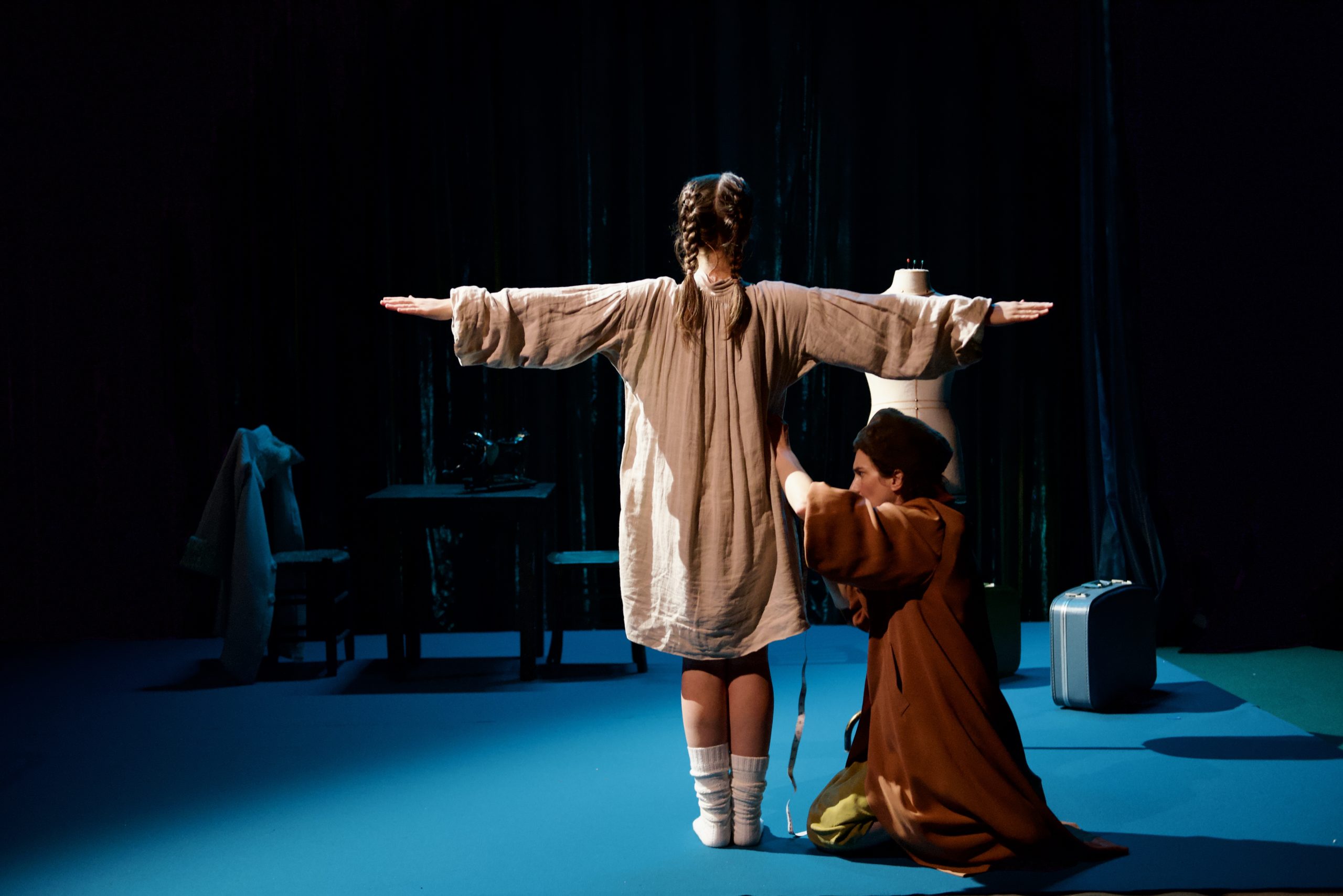 La petite fille essaie un manteau et sa maman l'ajuste. Dans le spectacle "Les Petites bêtes" © Anne-Cécile Pistenon