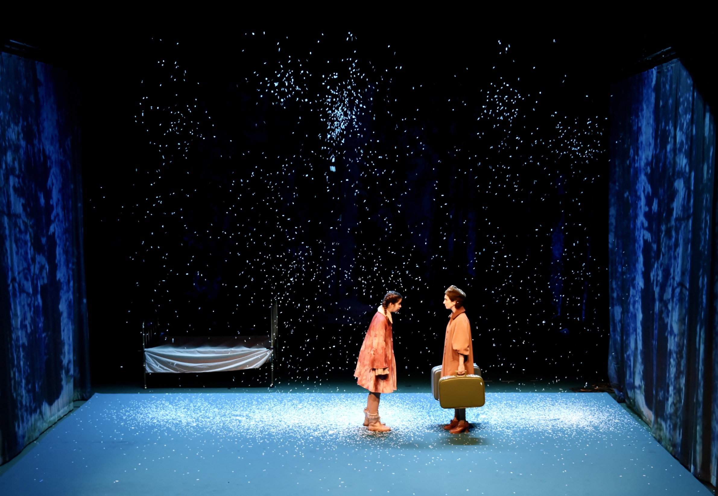 La petite fille et sa maman sous la neige avec des valises. Dans le spectacle Les Petites bêtes